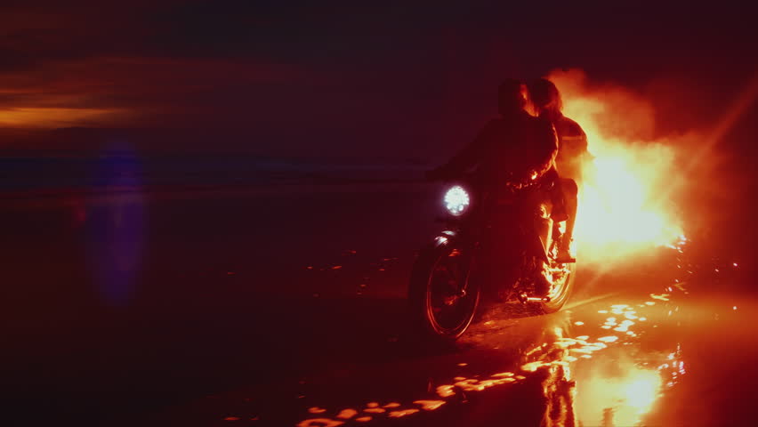 Romantic woman and man ride on moto bike, Bali Indonesia asia, twilling sunrise. Two young couples riding on vintage motorcycles with red burning signal flares after sunset on beach, slow motion fire