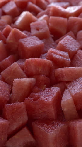 Watermelon chunks background. Selective focus, table spin, vertical video.