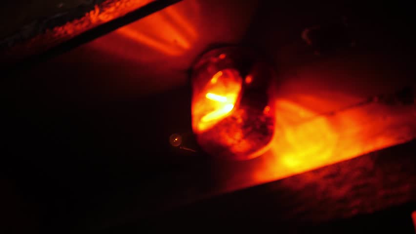 Close-up of a rotating red emergency siren lamp on the wall of a dark tunnel. A bomb shelter, an emergency signal on the wall during an air raid.