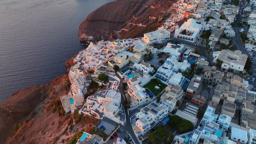 Sunset drone flight over Fira in Santorini, revealing Imerovigli and Oia along the caldera’s dramatic edge in golden light