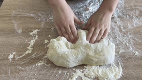 The hands of a female cook knead a lump of dough on a wooden table with white wheat flour. - Powered by Shutterstock - Get 15% off with code: PIKWIZARD15