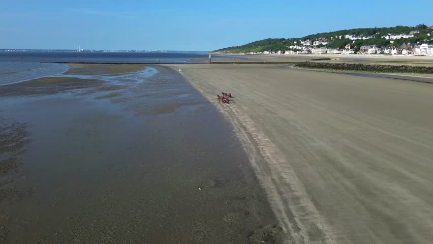 drone footage of trotters racing along the wide, sunlit beach of Deauville in Normandy