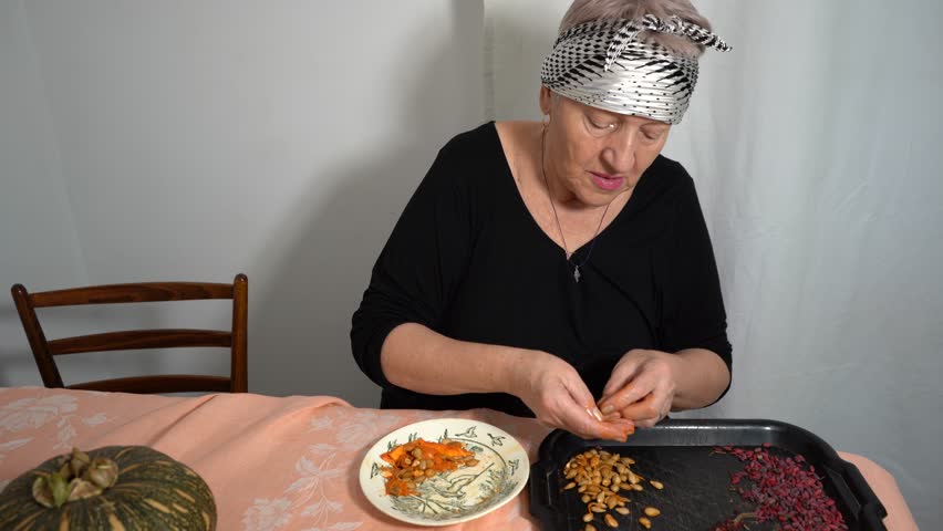 Picking pumpkin seeds to dry. An elderly woman dries barberry seeds. A grandmother sits at the kitchen table and cooks. Dry food