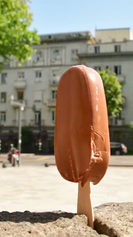 Vertical time lapse Ice cream melts rapidly under intense sun heat during summer morning in city. Symbolic visual metaphor global warming, rising temperatures, urban heat islands, public health danger