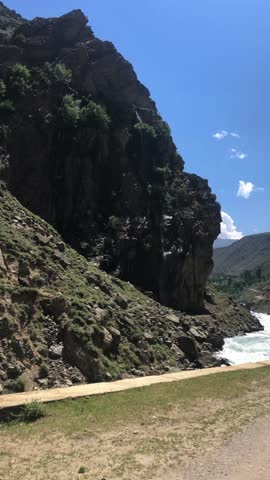  Vertical travel video on a dangerous road from Astore to Chilam Chowki, Skardu, Pakistan. Fast-flowing river on one side, solo biker are traveling on rocky mountains on the other.