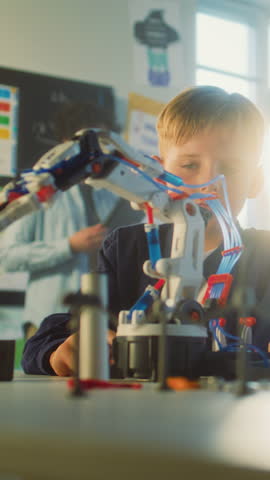 Team of Talented Boy and Girl Studying Robotic Arm Model. Primary School Children and Teacher During Science and Technology Lesson in Classroom. Interactive Learning, STEM Education. Vertical Shot.
