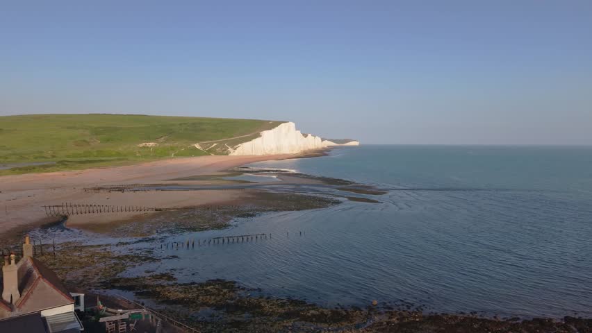 Drone glides past the white cliffs of Seven Sisters, revealing the Coastguard Cottages perfectly placed at a dramatic coastal edge