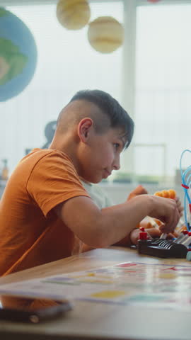 Teacher and Kids Doing Team Huddle Gesture in Multiethnic STEM Classroom. Primary School Children Exploring Robotics and Renewable Energy Models, Celebrating Teamwork. Slow Motion. Vertical Shot.