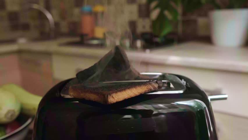 Burnt toasts in toaster with smoke rising kitchen fail concept representing a ruined breakfast and cooking mistake at home