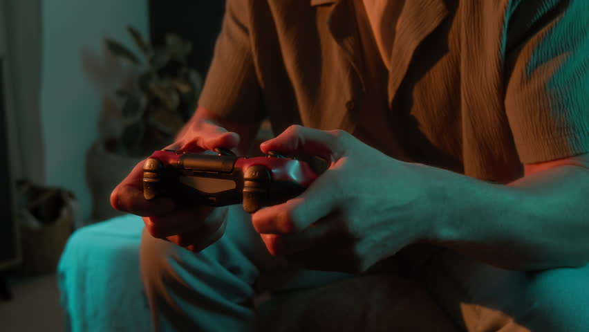 Close up of unrecognizable male hands holding joystick while playing video game at home
