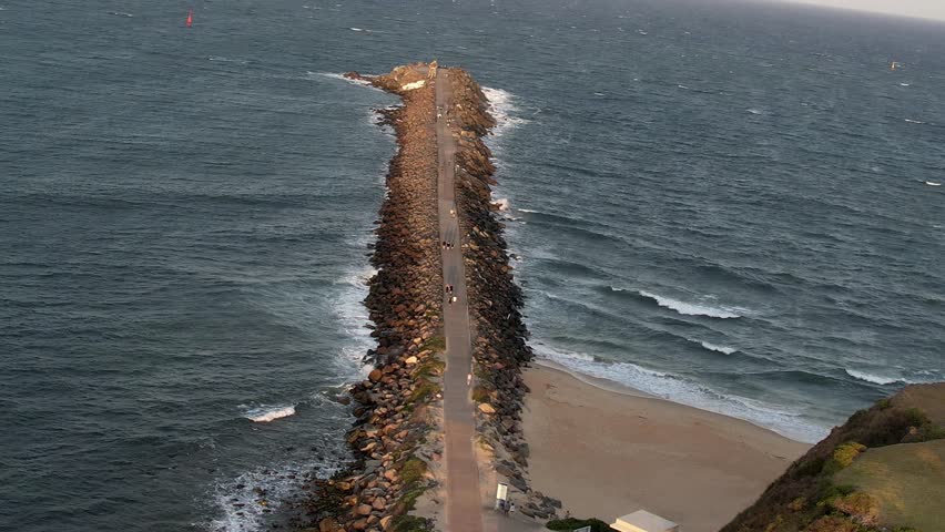 Newcastle, New South Wales, Australia, Breakwater stretching into the deep blue sea under a clear sky. The serene scene showcasing the harmony of ocean waves and sky hues