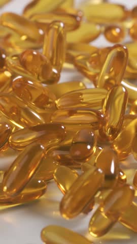 Vitamins and supplements fall onto a table in slow motion. Vertical Video.