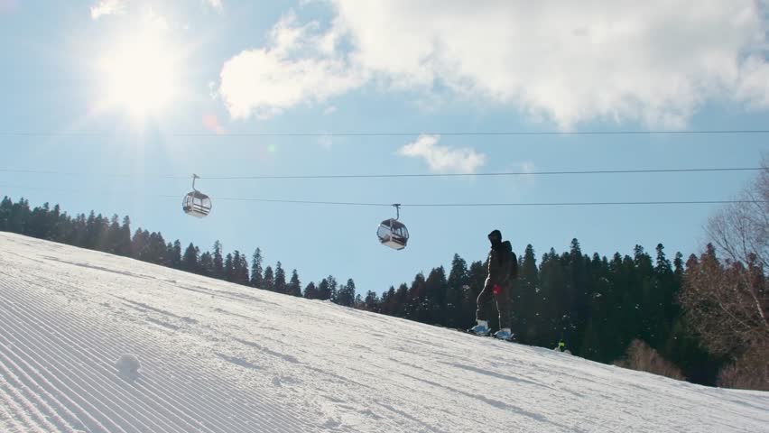 Young male beginner skiers friends enjoy skiing on groomed snow slope under bright winter sun during ski vacation learning to ski in ski resort. Intentional out of focus background copy space