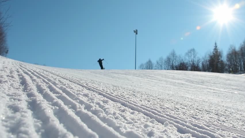 Group of young experienced skiers ski jump downhill enjoy winter sunny morning freshly groomed slope.Intentional out of focus. textured groomed ski slope.