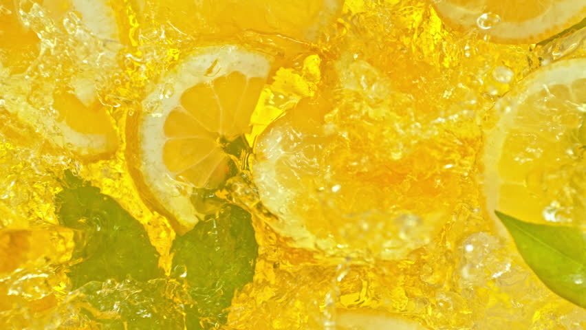 Super Slow Motion Shot of Pouring Lemonade on Fresh Lemon Slices, Ice and Green Leaves at 1000fps.