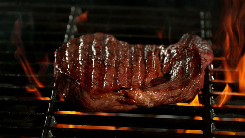 Super Slow Motion Shot of Tasty Beef Steak Meat on Fired up Grill at 1000fps.