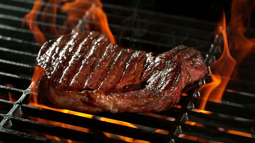 Super Slow Motion Shot of Tasty Beef Steak Meat on Fired up Grill at 1000fps.