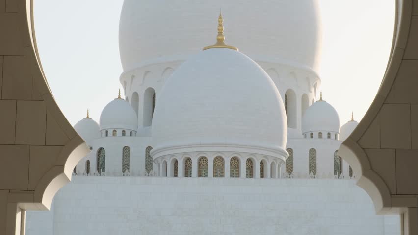 View of Domes of Sheikh Zayed Grand Mosque in Abu Dhabi, UAE framed by ornate arch. Islamic art and architecture. Popular Arabic place of worship and a landmark