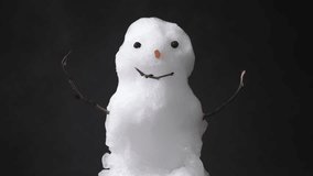 A small snowman melts gradually in this horizontal real-world video. Classic snow texture and iconic features on black background. - Powered by Shutterstock - Get 15% off with code: PIKWIZARD15