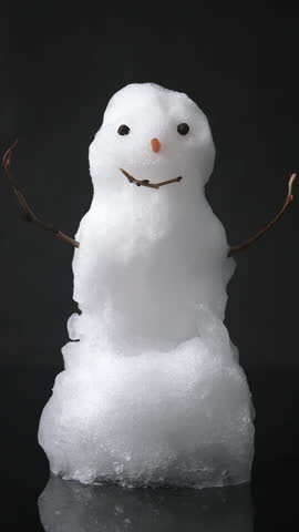 A real snowman slowly melts on camera in this vertical live-action shot. Classic details and natural texture, isolated on black.