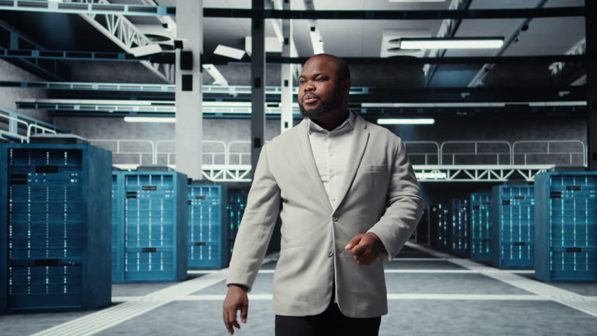 Portrait of smiling admin doing yearly checkup to prolong data center electronics life span and avoid downtime. Upbeat worker walking in server room, monitoring infrastructure rigs, camera A