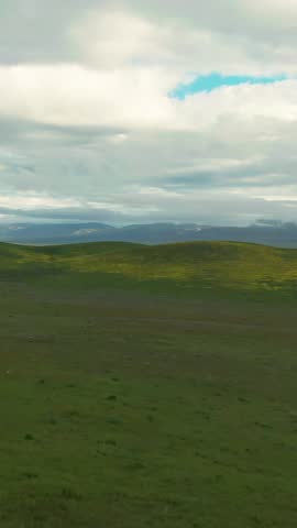 Rolling green hills under a cloudy sky in Carrizo Plain National Monument, California, USA. The landscape is peaceful and serene, showcasing the natural beauty of the region.