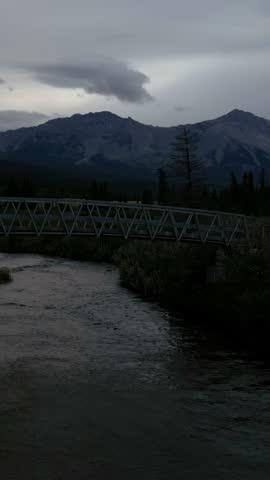 Majestic Mountains and a Flowing River Under a Bridge in Beautiful Alberta, Canada