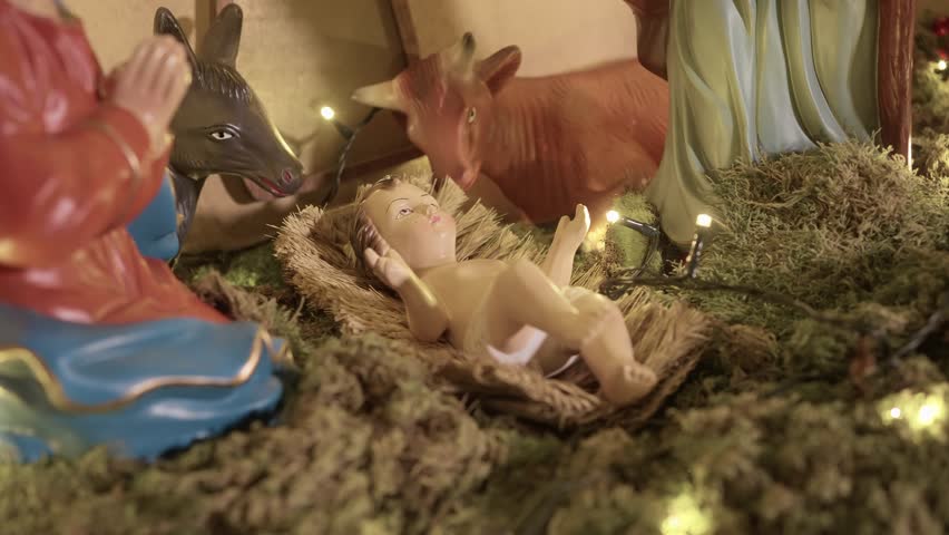 nativity scene with baby jesus in straw lit by soft festive lights