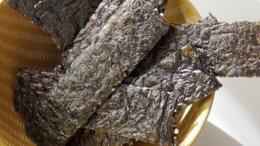 Crispy seaweed snack in a bowl with light reflections