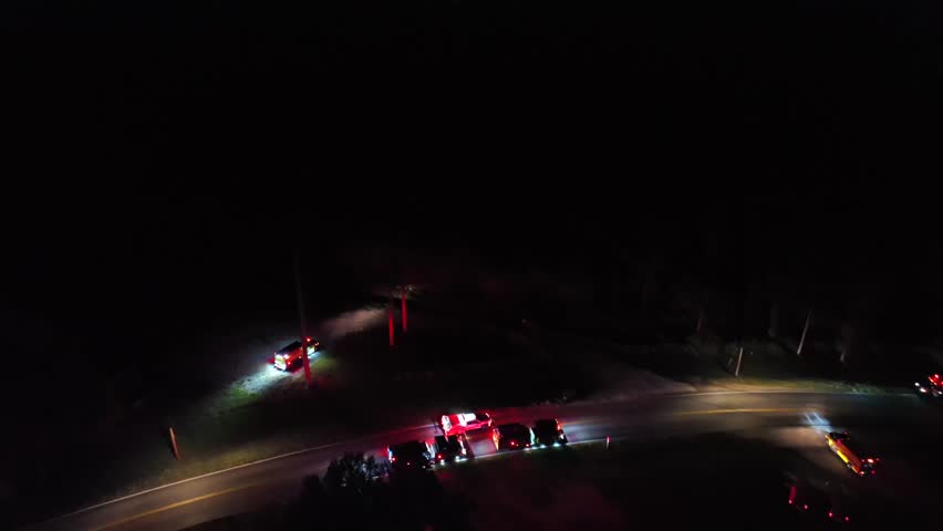 Fire trucks and emergency vehicles arriving accident scene at night. Rural american interstate road. Aerial top down shot. Flashing lights of vehicles.