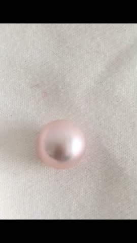 Close-Up of a Single Shiny Pink Pearl on Soft Fabric Background