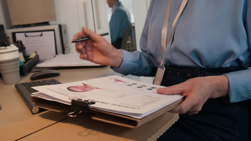 Tilt up shot of mature Caucasian counselor or investigator checking criminal profile of inmate while sitting at desk