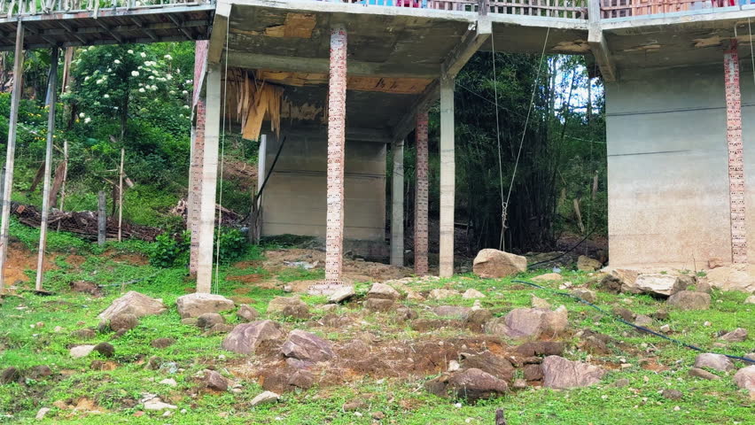 Elevated concrete home built on stilts in Tả Van village, Vietnam. Traditional architecture adapted to hilly terrain, surrounded by rocks and greenery.