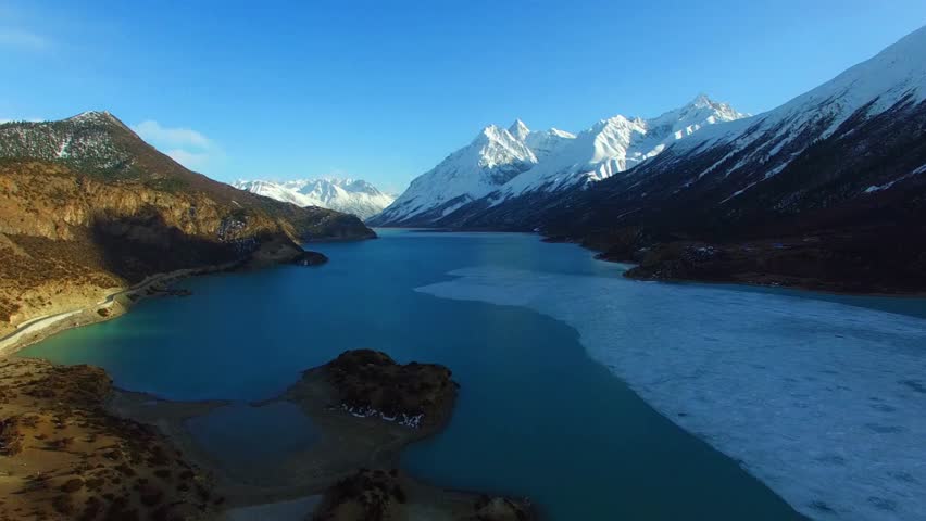 Snow capped mountains surround a pristine blue lake landscape