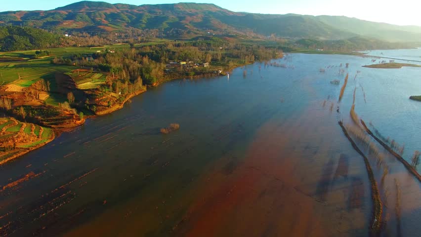 Scenic landscape of a lake surrounded by mountains and agricultural fields