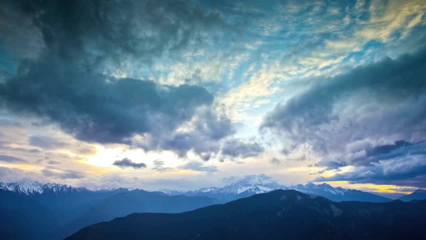 Dramatic mountain range under a cloudy sky at sunset