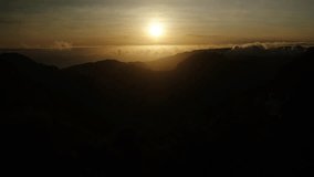 Golden sun sets over layered mountain ridges as two people sit quietly in shadow, watching the horizon glow. - Powered by Shutterstock - Get 15% off with code: PIKWIZARD15