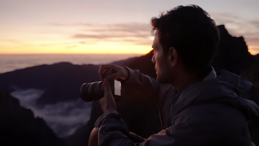 Man captures the mountain sunset through his camera viewfinder, focused on composing the perfect shot.