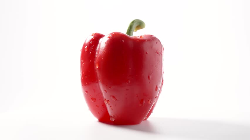 Whole Red Bell Pepper. A whole red bell pepper rotates slowly, covered in droplets. The vibrant red color and glossy skin are highlighted.