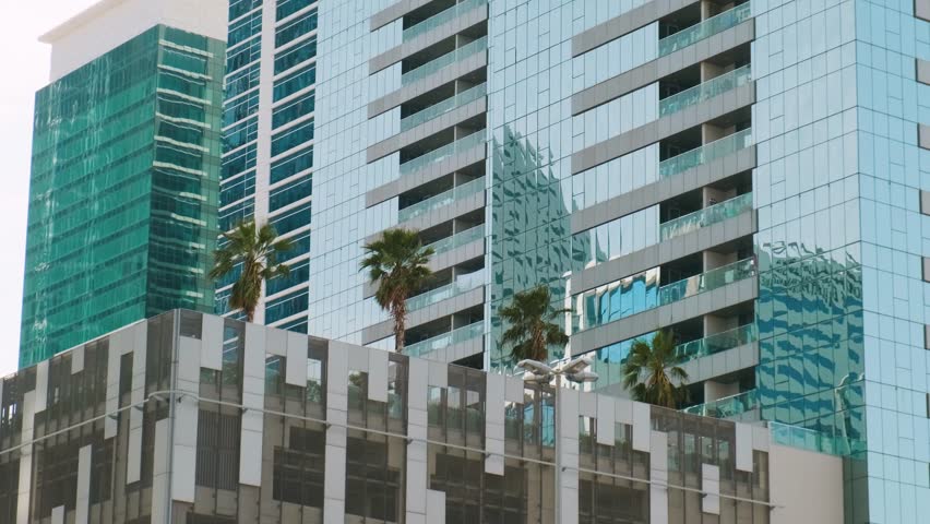 Modern high-rise buildings with reflective glass facades and palm trees growing on rooftop in Dubai city, UAE. Eco friendly urban environment. Sustainable modern and ecological architecture - Powered by Shutterstock - Get 15% off with code: PIKWIZARD15