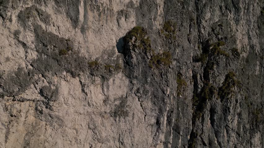 Flying up Along Rocky Cliff Wall, Aerial view of Steep Rock Face