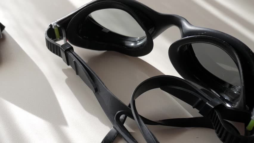 Swimming goggles, earplugs, and a swim cap arranged neatly, ready for use
