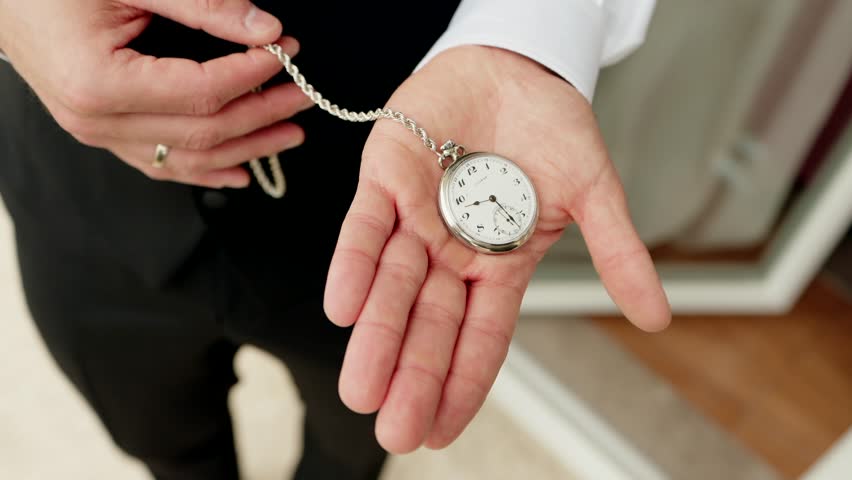 close up of groom displaying classic silver pocket watch