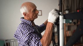 Elderly man fixing bicycle at home, tightening fender on wheel using wrench. Concept of maintenance, fixing, repair and preparing bicycle for new season - Powered by Shutterstock - Get 15% off with code: PIKWIZARD15