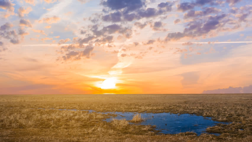dramatic sunset over a prairie with small lake time lapse scene