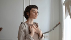 Relaxed young woman breathing deeply with hands resting on chest, turning inward for reflection. Meditation practice, zen spiritual connection, mindfulness routine, emotional balance, inner peace - Powered by Shutterstock - Get 15% off with code: PIKWIZARD15
