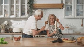 Enjoy simple life and be happy, old wife and husband dancing in home kitchen. Elderly lady singing into rolling-pin, aged man dancing with wooden spoon, fun and joy, merry weekend of senior spouses - Powered by Shutterstock - Get 15% off with code: PIKWIZARD15
