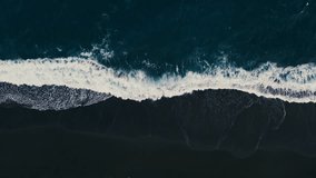 An aerial view captures the rhythmic ocean waves meeting the stunning black sand, creating a mesmerizing visual harmony that enchants and draws in the viewer with its captivating allure - Powered by Shutterstock - Get 15% off with code: PIKWIZARD15