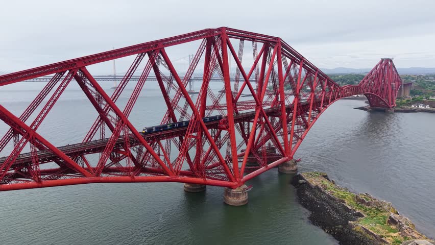 Aerial footage of train crossing Forth Bridge, Scotland, United Kingdom