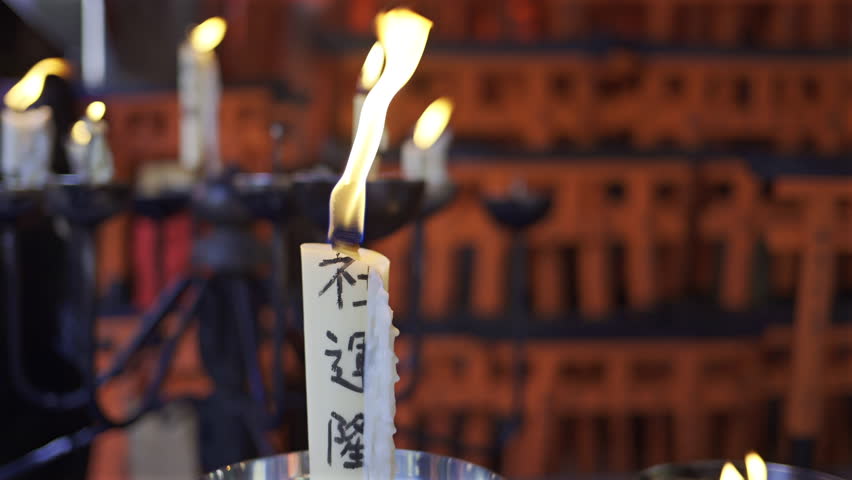 Fushimi Inari Shrine in Japan with candles flickering gently, illuminating inscriptions and creating a peaceful atmosphere. Translation on candle: 